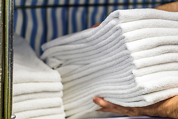 Freshly laundered white towels being prepared in a laundry facility