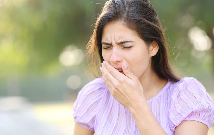 woman outside coughing into hand