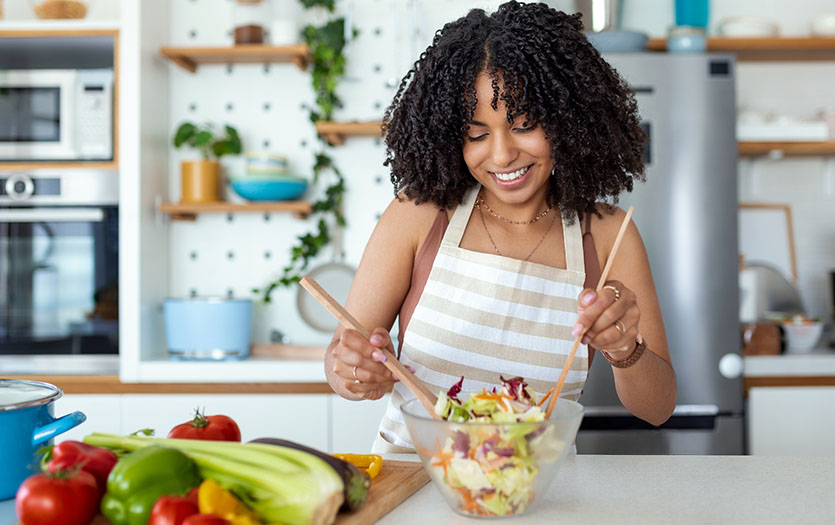 woman smiling and making salad