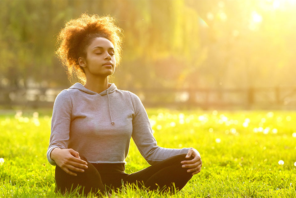 Woman meditating in forest sitting in meditation pose leaning